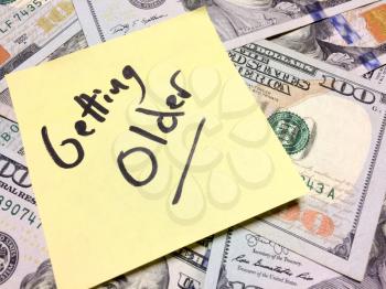 American cash money and yellow post it note with text Getting Older in black color aerial view