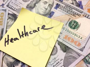American cash money and yellow paper note with text Healthcare in black color aerial view