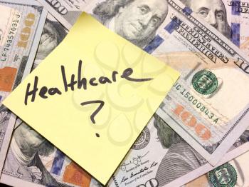 American cash money and yellow paper note with text Healthcare with question mark in black color aerial view