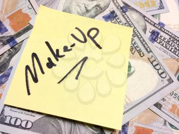 American cash money and yellow sticky note with text Make-up in black color aerial view