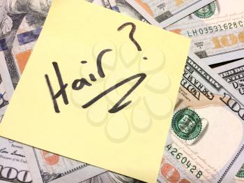 American cash money and yellow sticky note with text Hair with question mark in black color aerial view