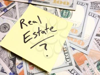 American cash money and yellow sticky note with text Real Estate with question mark in black color aerial view