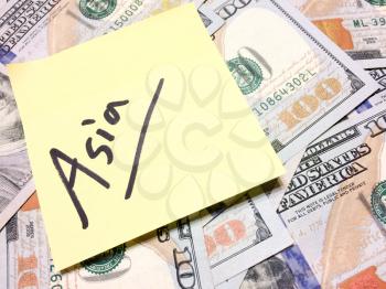 American cash money and yellow sticky note with text Asia in black color aerial view