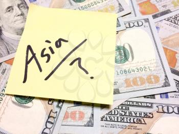 American cash money and yellow sticky note with text Asia with question mark in black color aerial view
