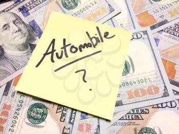 American cash money and yellow sticky note with text Automobile with question mark in black color aerial view