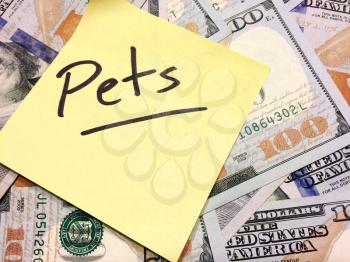 American cash money and yellow sticky note with text Pets in black color aerial view
