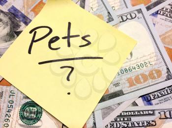American cash money and yellow sticky note with text Pets with question mark in black color aerial view