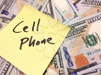 American cash money and yellow sticky note with text Cell Phone in black color aerial view