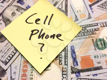 American cash money and yellow sticky note with text Cell Phone with question mark in black color aerial view