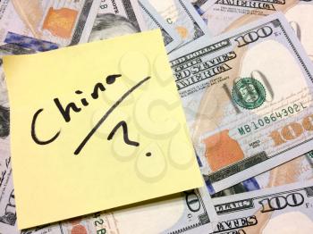 American cash money and yellow sticky note with text China with question mark in black color aerial view