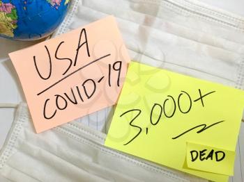 USA Coronavirus COVID-19 infection medical cases and deaths United States. China COVID respiratory disease influenza virus statistics hand written on surgical mask and earth globe background