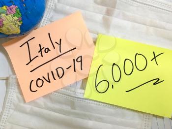 Coronavirus COVID-19 Italy infection medical cases and deaths. China COVID respiratory disease influenza virus statistics hand written on surgical mask and earth globe background