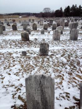 Old cemetery gravestones with snow on cold winter day