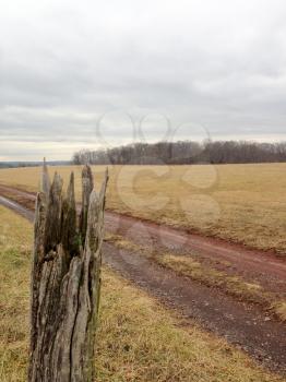 Old wooden fence post landscape country farm with cloudy sky and country road