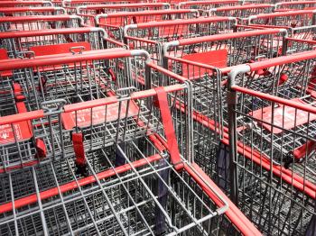 red and silver metal shopping carts organized in mass rows making square patterns
