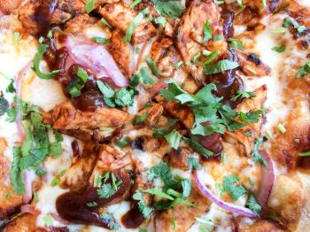 Gourmet bbq barbecue chicken sauce pizza bread and red onion basil parsley close up