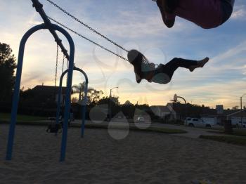 Kids girls on swing and sunset or sunrise
