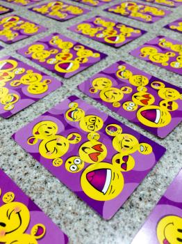 Happy face smiely emoji on playing cards purple color on table