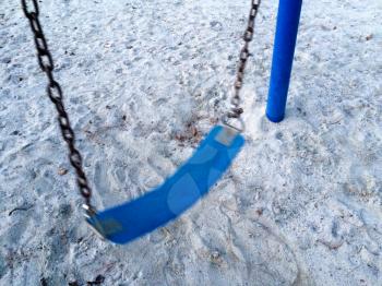 Empty swing at playground blue seat over gray sand