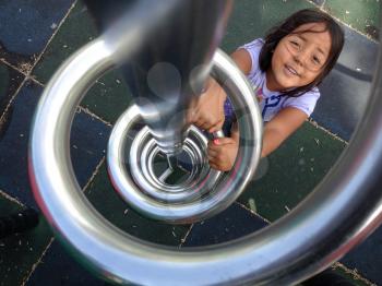 cute kid girl smiling at playground climbing up ladder spiral