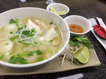 Vietnamese pho chicken noodle soup on tray at restaurant