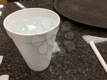 Styrofoam cup plastic straw white on black restaurant table