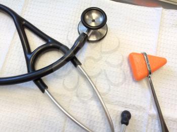 Stethoscope rubber reflex hammer on white tray doctors medical exam room equipment