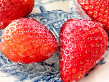 Wet juicy luscious strawberries shiny on blue white dutch plate