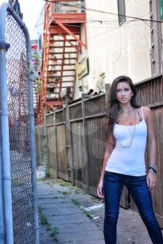 Sexy beautiful female brunette long hair jeans in alley gritty city