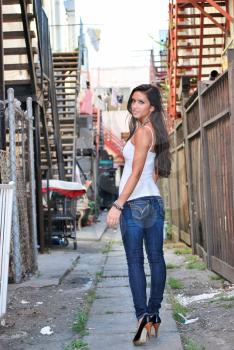 Sexy beautiful female brunette long hair jeans in alley gritty city