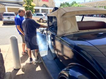 1934 Ford Roadster blue at gas station with men talking