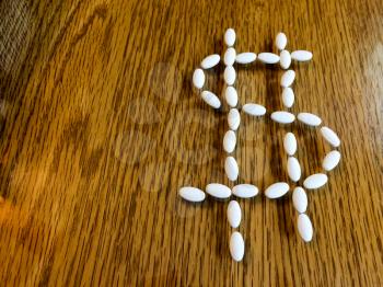 Medicine pills making dollar money sign showing expensive