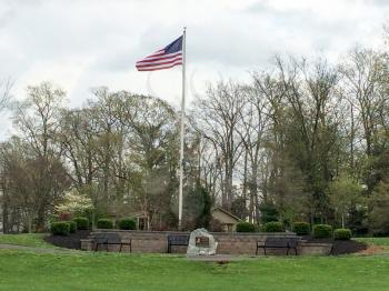 american flag waving in park with green grass and sky