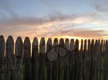 sunset green grass rustic wooden fence with yellow blue gold colors and tree