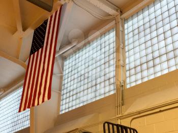 American flag hangs high inside building gymnasium skylight