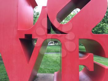 Love art text in big red metal letters in park with grass