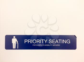 Priority seating sign in blue color on white wall