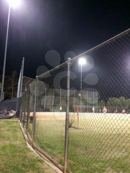 Night time baseball game at playing field outdoor with people and kids