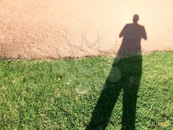 tall big single human man shadow on ground of grass and dirrt
