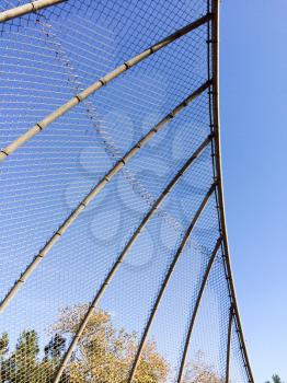 Geometric design element chain link baseball backstop fence and blue sky