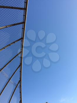 Geometric design element chain link baseball backstop fence and blue sky