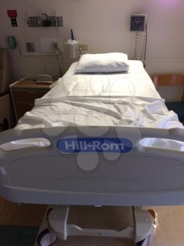 hospital bed empty in room with white sheets