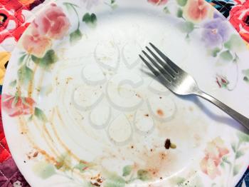 Empty dinner plate dirty with fork after yummy saisfying meal