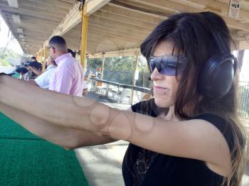 shooting range outdoor with cute girl holding self defense handgun firearm aiming target
