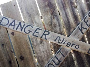 Danger keep out peligro sign painted on wood fence rustic