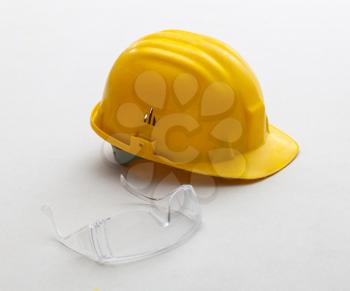 Yellow helmet and glasses for work safety on plasterboard panels.