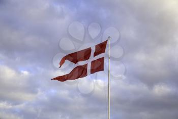 Flag of Denmark waiving in the wind and blue sky as the background