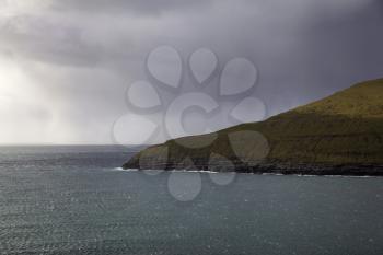 View of Vagar island with stormy sky across the fjord Kalsoy, Faroe Islands