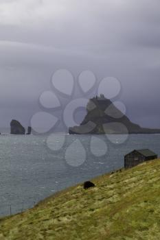 Tindholmur and Drangarnir with dramatic stormy sky as background, Faroe Islands