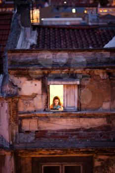 A view over an open illuminated window with a person in iconic neighbourhood of Baixa in Lisbon